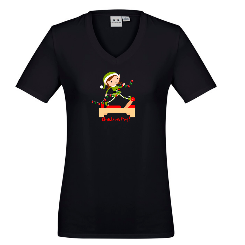 black v neck womens  tee with an elf performing front splits pilates exercise on the reformer carrying christmas lights - with the title christmas prep