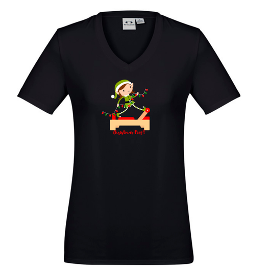 black v neck womens  tee with an elf performing front splits pilates exercise on the reformer carrying christmas lights - with the title christmas prep