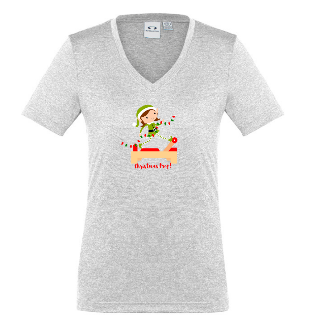 silver v neck womens tee  with an elf performing front splits pilates exercise on the reformer carrying christmas lights - with the title christmas prep