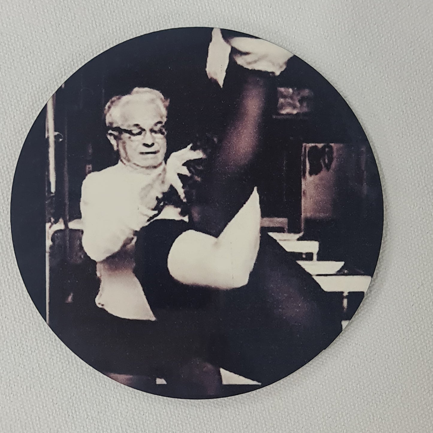 Round cork coaster featuring joseph pilates teaching squirrel to a client on the trapeze table