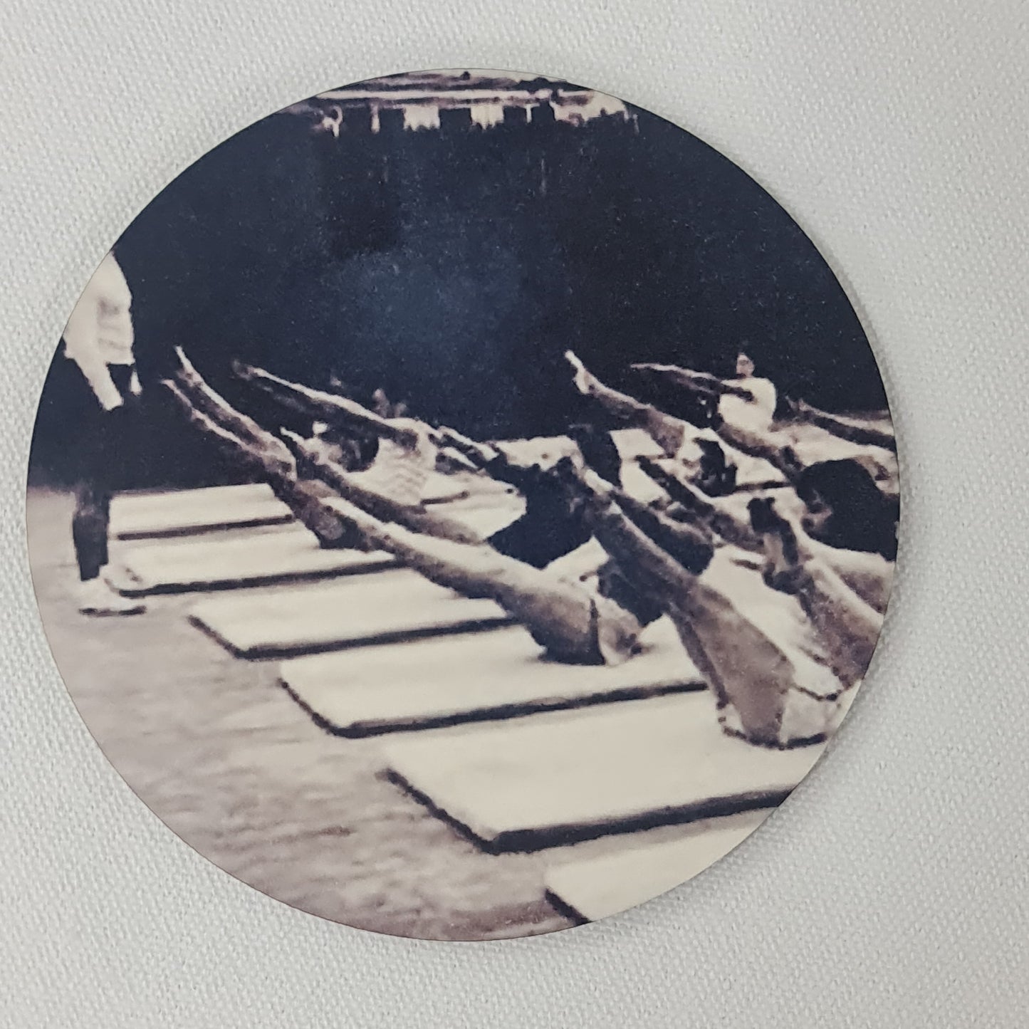 Round cork coaster featuring a pilatesa mat class group being taught teaser by jospeh Pilates - pilates classic in black and white