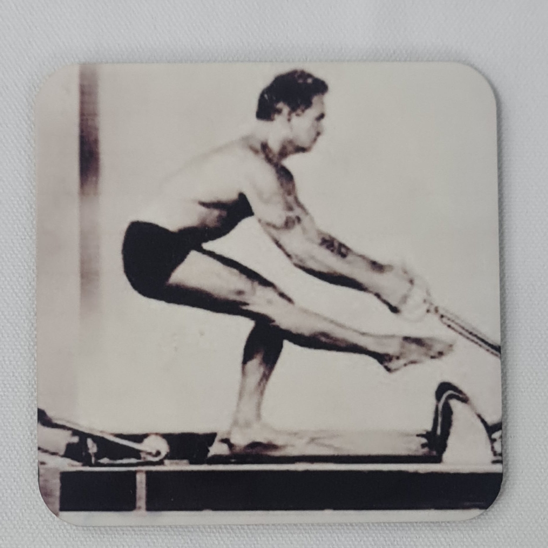 classic pilates exercuise oin the reformer of man facing back performing arms series in a single leg squat - pilates drinks coaster