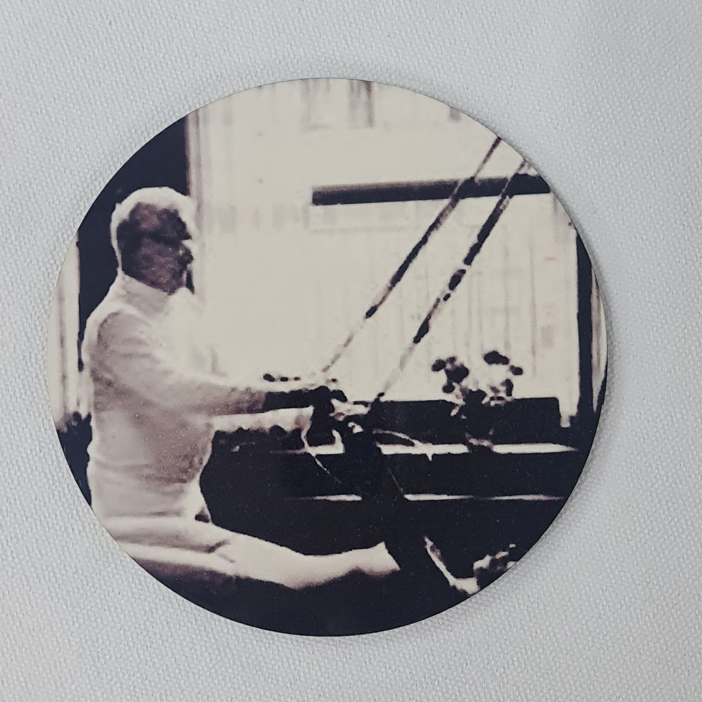 Round cork coaster featuring joseph pilates teaching the exercise 'breathing' on the trapeze table - black and white classic