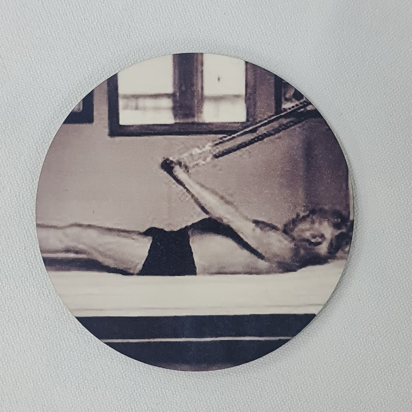 Round cork coaster featuring - black and white classis photo of joepsh pilates performing assisted hundred on the trpaeze table