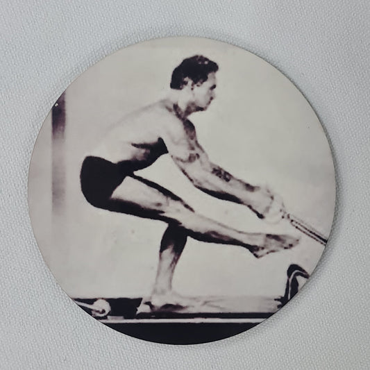 Round cork coaster featuring pilates exercises on the reformer - single leg squat using arms series.